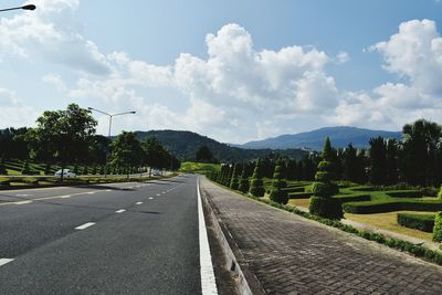 Empty road along trees and against sky