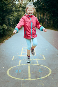 Active little girl playing hopscotch on playground outdoors. jumping for joy. children activity