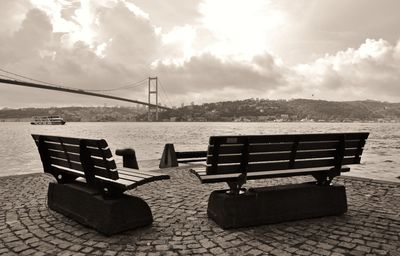 Bench by sea against sky