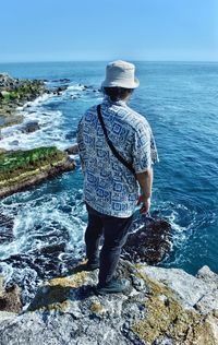 Rear view of man looking at sea against sky