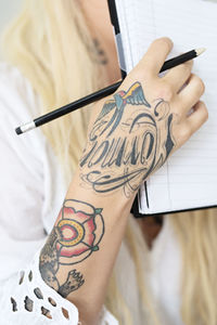 Woman with tattoos holding notebook, close-up