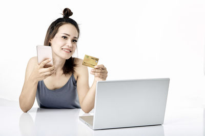 Portrait of smiling young woman using phone against white background