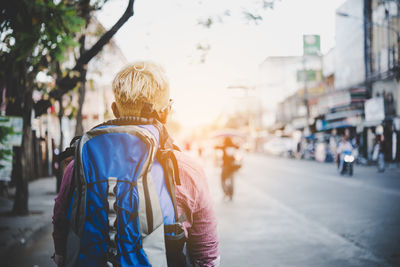 Rear view of man standing on road in city