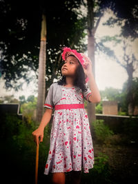 Girl looking away while standing against pink flowers