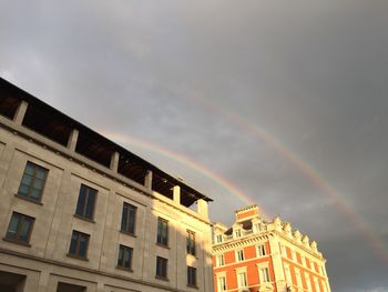 Low angle view of rainbow over buildings against sky