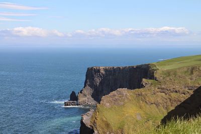 Scenic view of cliff by sea against sky