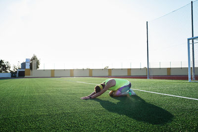 Young man practices stretching on the grass after his daily training