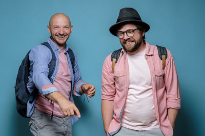 Portrait of friends standing against blue background