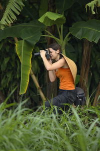 Woman photographing in grass