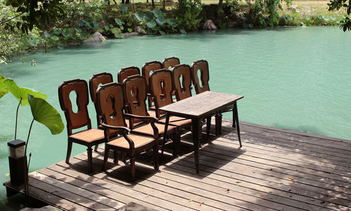 High angle view of empty chairs and table on pier over lake