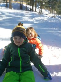 Portrait of siblings sitting on snow covered land