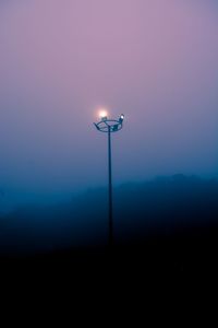 Illuminated street light against sky at night