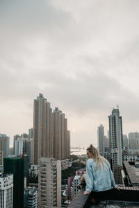 Woman standing by cityscape against sky