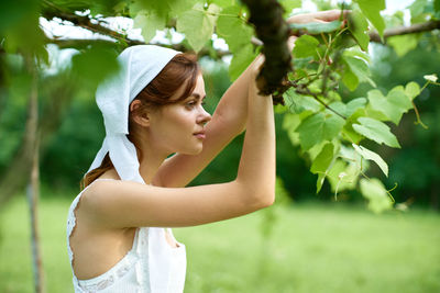 Side view of young woman holding flowers