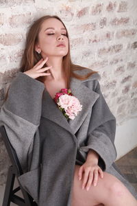 Fashion model wearing warm woolen gray coat decorated with pink  roses, spring floral theme