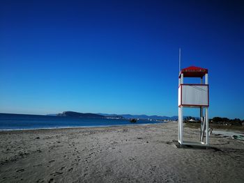 Lifeguard hut on beach against clear blue sky