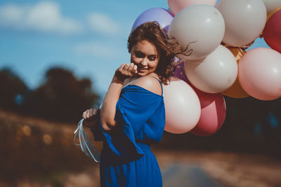 Portrait of young woman with balloons standing outdoors