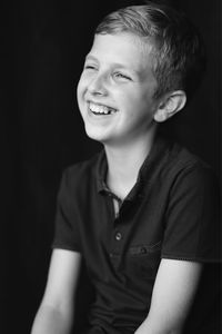 Portrait of young man looking away against black background