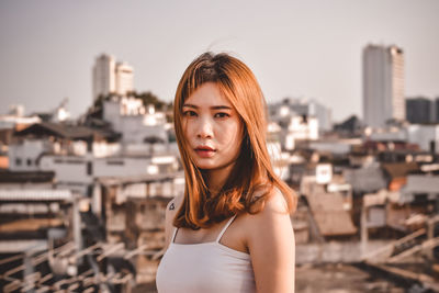 Portrait of beautiful woman standing against cityscape