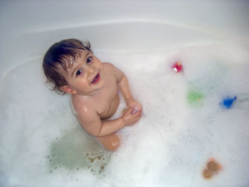 Happy little baby boy having a bubble bath