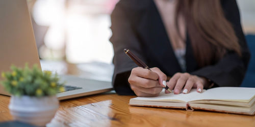 Midsection of woman reading book on table