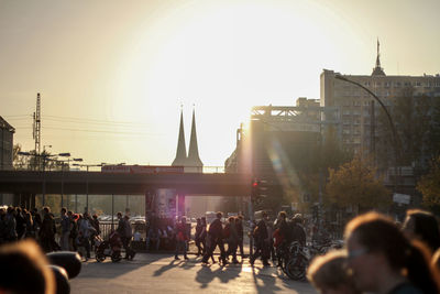 People walking on city street during sunset