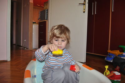 Cute boy sitting while playing with blocks at home