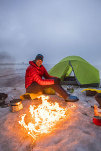 Portrait of mounatineer siting by campfire, camping on glacier