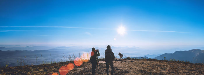 Rear view of people walking on mountain against sky