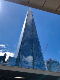 Low angle view of modern glass building against blue sky