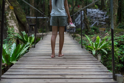 Rear view of woman walking on footbridge