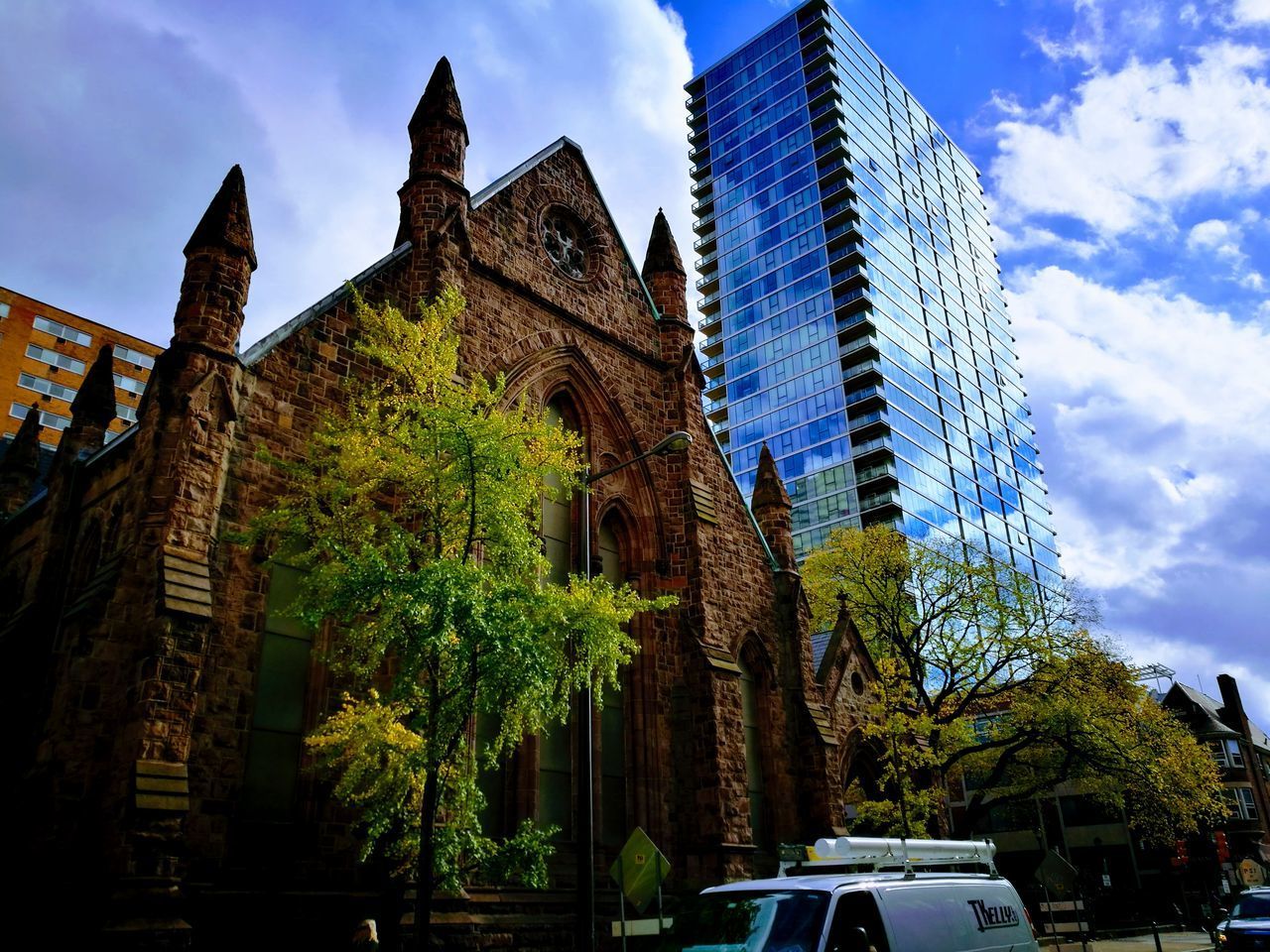 LOW ANGLE VIEW OF TREES BY BUILDINGS AGAINST SKY