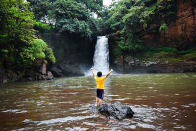 Full length of boy surfing on rock in forest