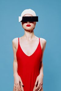 Portrait of young woman standing against blue background