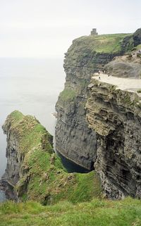 Scenic view of cliff by sea against sky