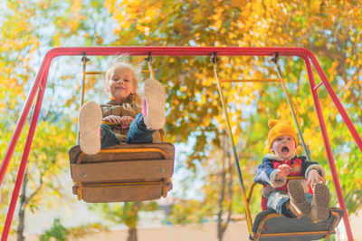 Rear view of people sitting on slide at playground