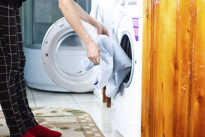 Low section of woman washing clothes in washing machine