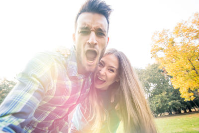 Portrait of smiling young man and woman against sky