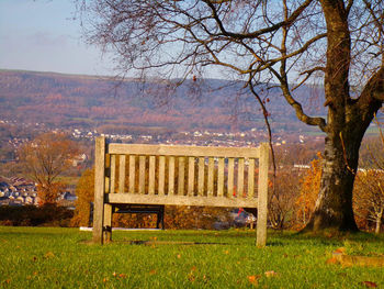 Park bench on field against sky during autumn