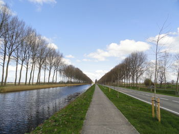 Road by canal against sky