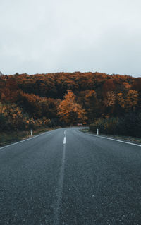 Road amidst trees against sky during autumn