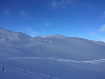 Scenic view of snowcapped mountains against blue sky