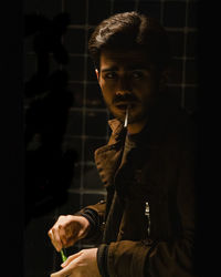 Young man looking away while standing against black background