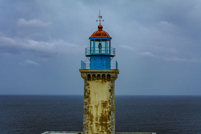 Lighthouse by sea against sky