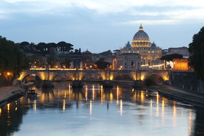 Arch bridge over river by buildings against sky