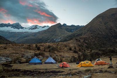 Tents on mountain against sky during sunset