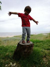 Boy jumping on sea shore against sky