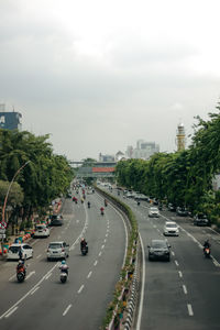 Vehicles on road in city against sky