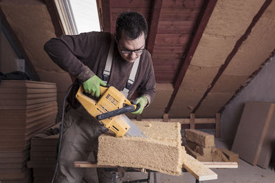 Roof insulation, worker cutting wood fibre insulation