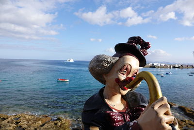 Young woman at beach against sky